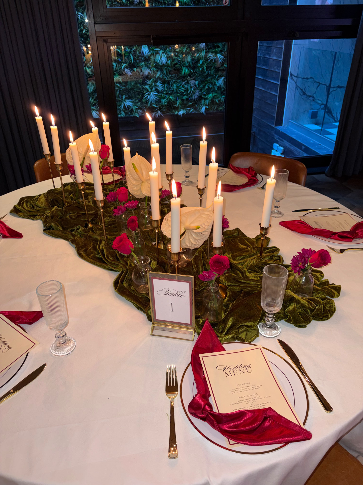 Candlelit table with velvet runner, red napkins and wedding menu